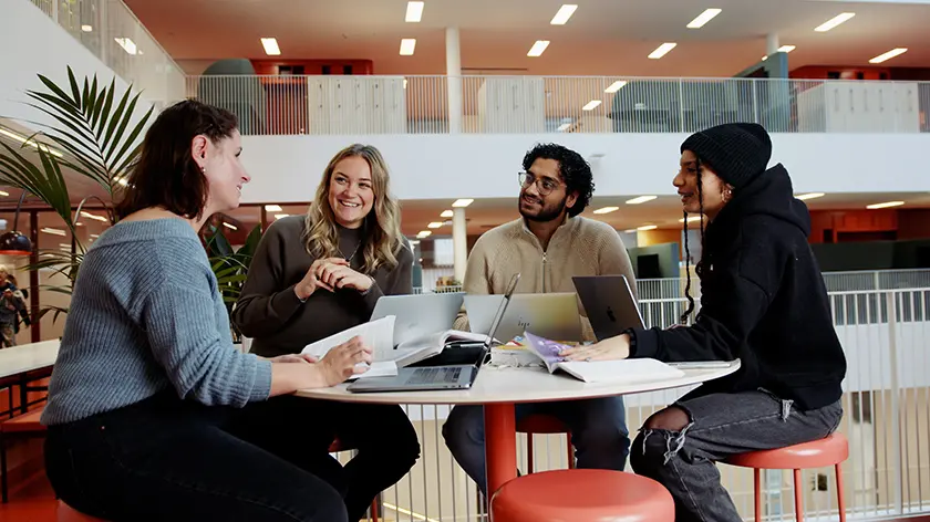 Studenter pratar glatt vid ett bord på Campus Eskilstuna